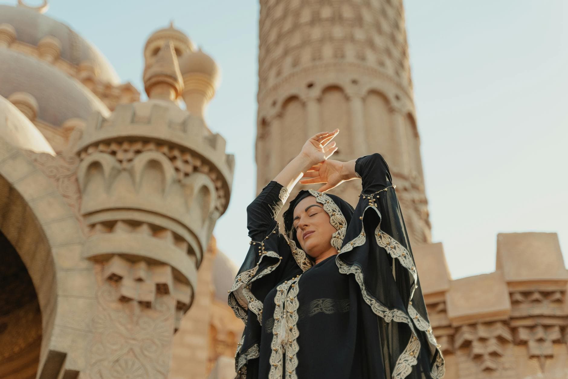 Photo by Tima Miroshnichenko on Pexels A woman in traditional abaya poses gracefully outside a mosque, embracing spirituality and culture.