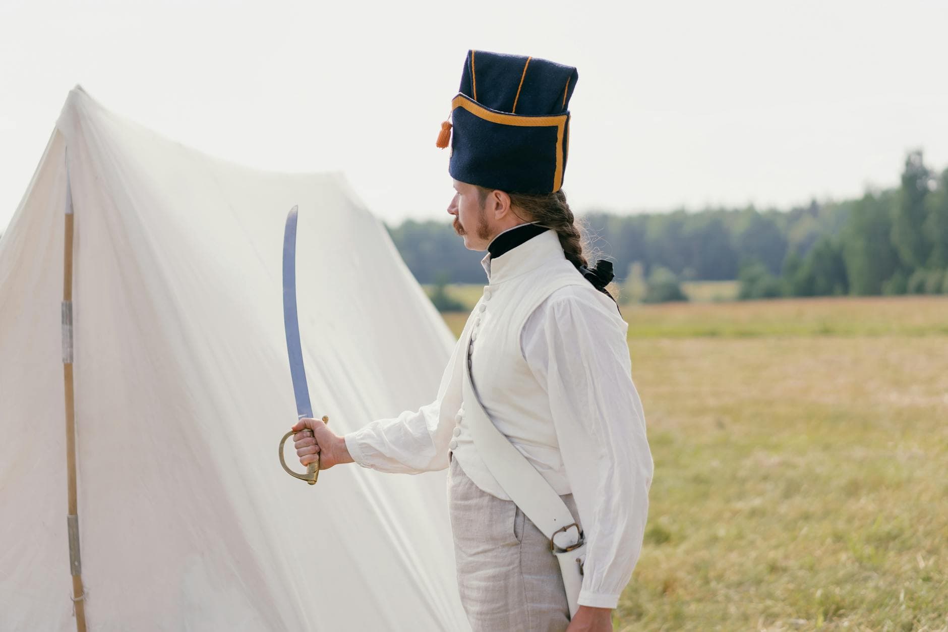 Photo by Mikhail Nilov on Pexels Side profile of a reenactor in historical military uniform with a sabre, outdoors.