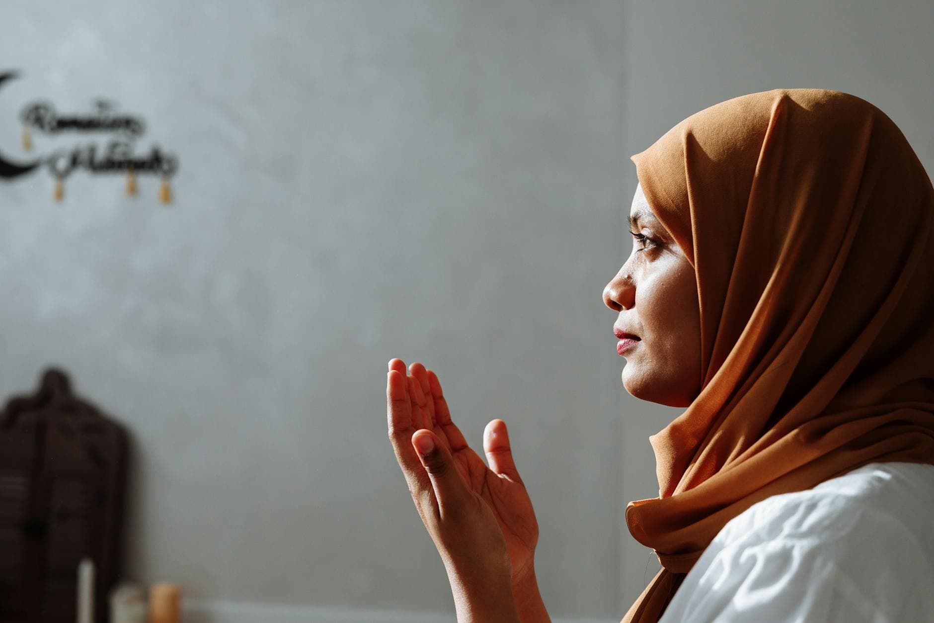 Photo by Thirdman on Pexels Side view of a Muslim woman in a brown hijab praying indoors with spiritual focus.