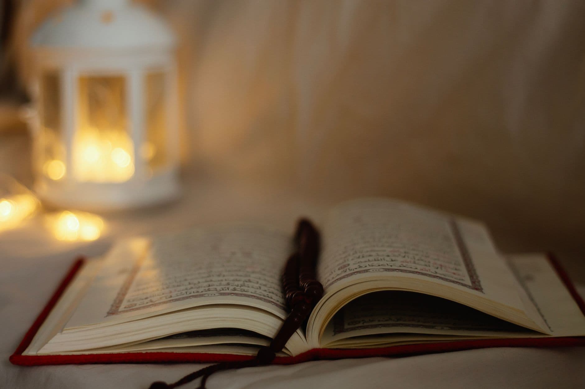 Photo by Sarah AlAmeri on Pexels An open Quran with a decorative lantern softly lit in the background, symbolizing spirituality.