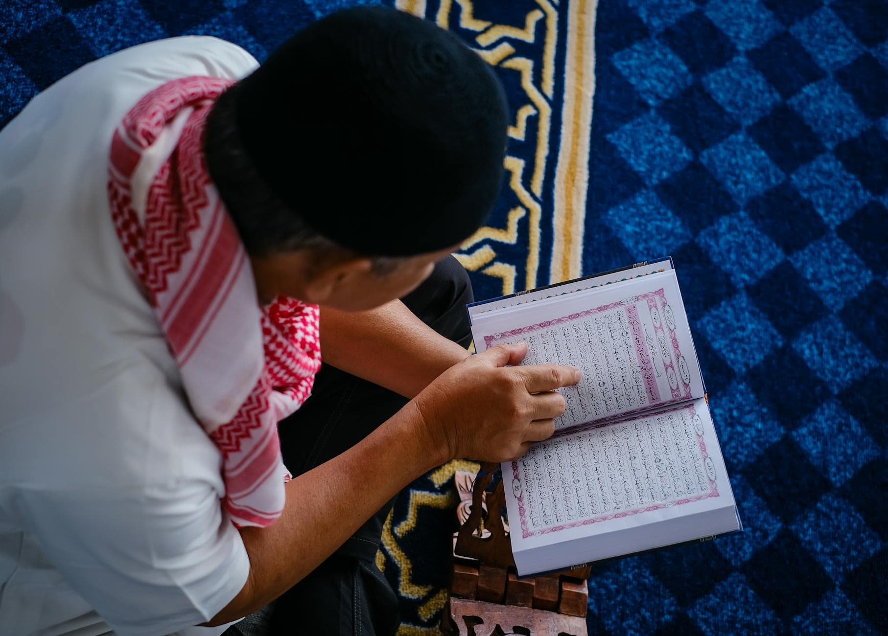Photo by Noval Gani on Pexels A Muslim man reading the Quran on a rehal inside a mosque, reflecting spirituality.