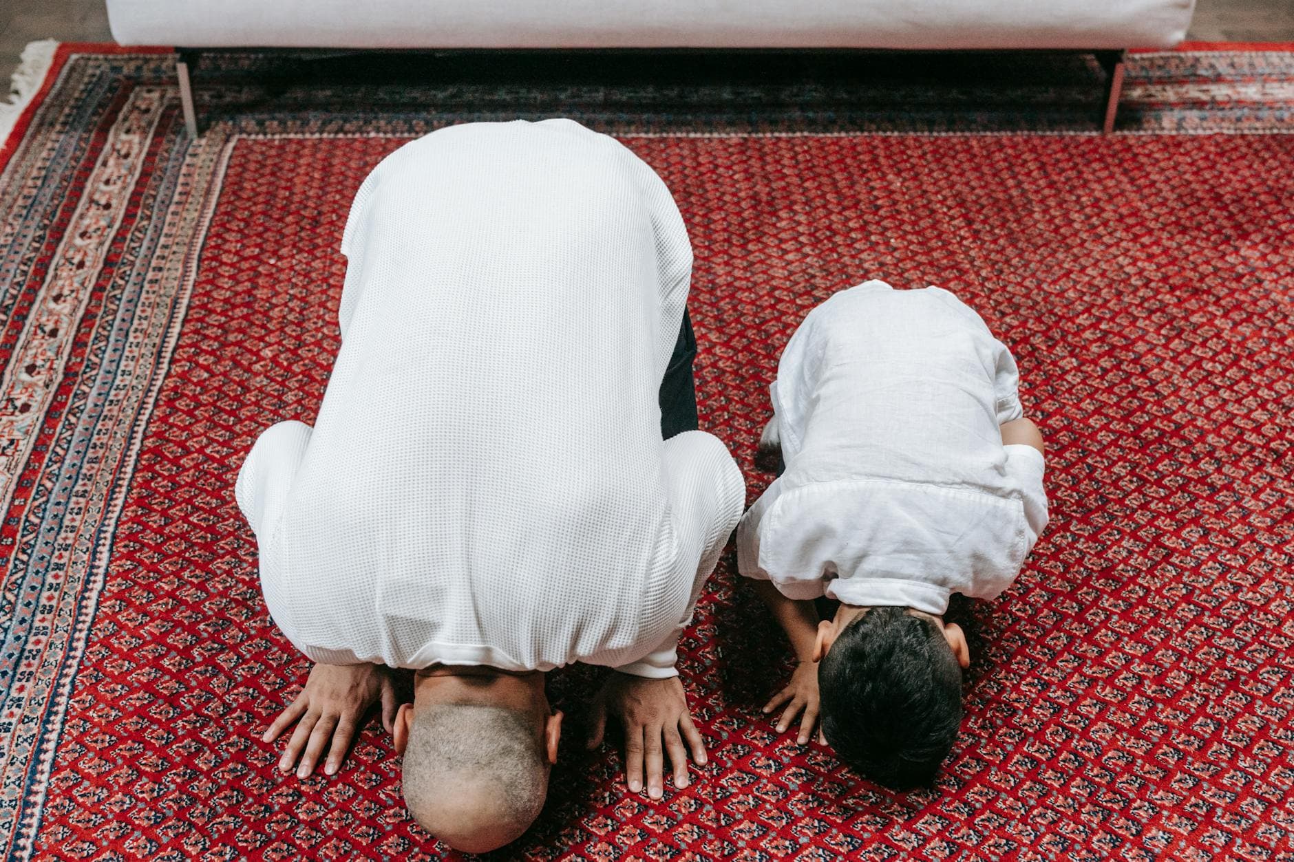 Photo by Timur Weber on Pexels A father and son bowing in prayer on a traditional rug indoors, displaying religious devotion.