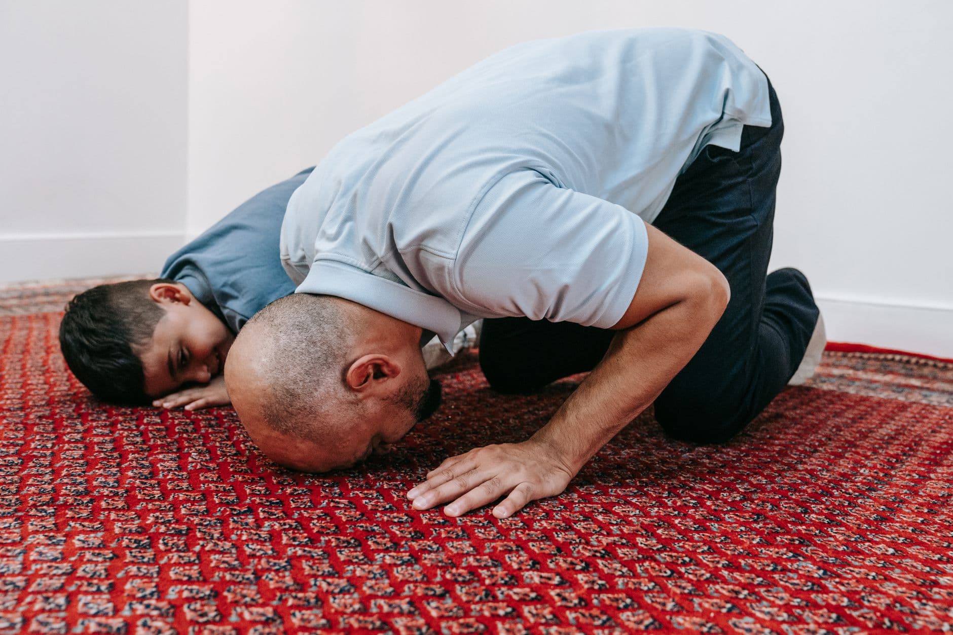 Photo by Timur Weber on Pexels A man and a child prostrating together in prayer, symbolizing devotion and spiritual unity.