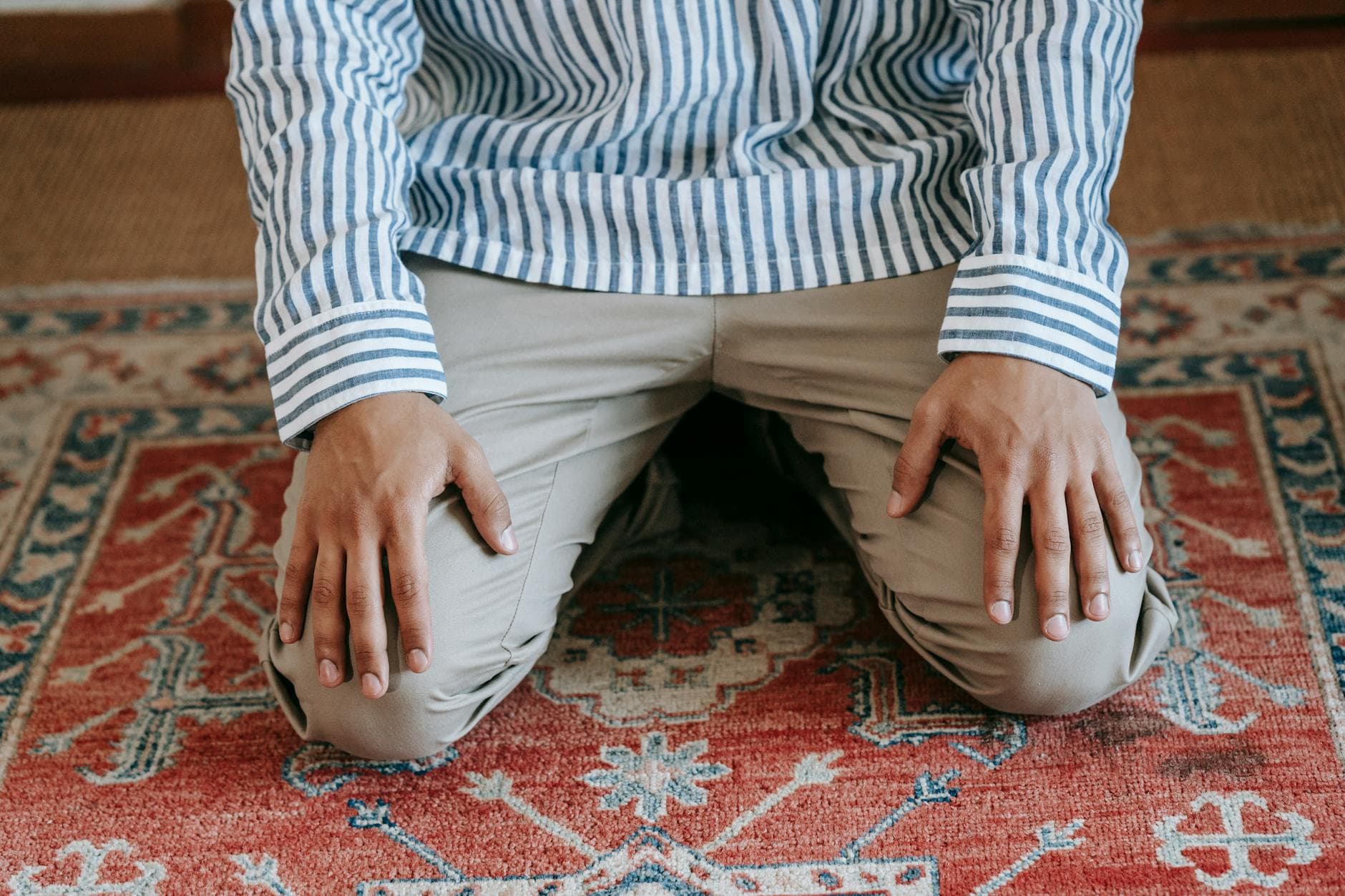Photo by Michael Burrows on Pexels A person kneeling on a patterned rug indoors, symbolizing Islamic prayer practices.